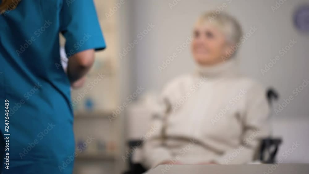 Therapist making notes in medical records and examining elderly lady, hospital Therapist making notes in medical records and examining elderly lady, hospital