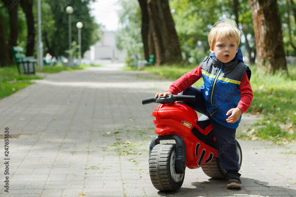 Cute Baby Boy Sitting On A toy Motorcycle in the park. copy space Cute Baby Boy Sitting On A toy Motorcycle in the park. copy space