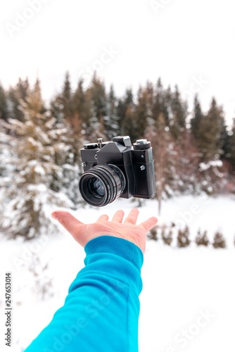 man doing levitation trick effect with 35mm film camera on snowy mountain.