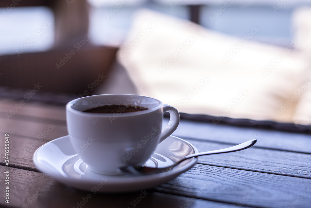 A small white porcelain espresso cup on a saucer with a teaspoon and two pieces of sugar A small white porcelain espresso cup on a saucer with a teaspoon and two pieces of sugar