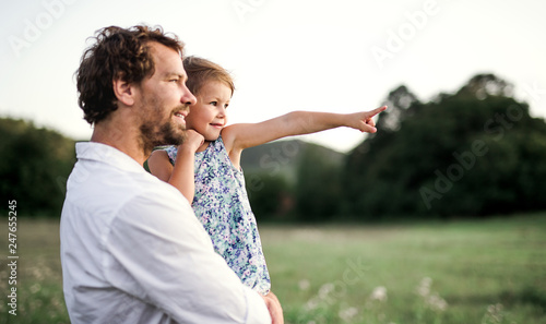 Young father in nature holding small daughter in the arms. Copy space.