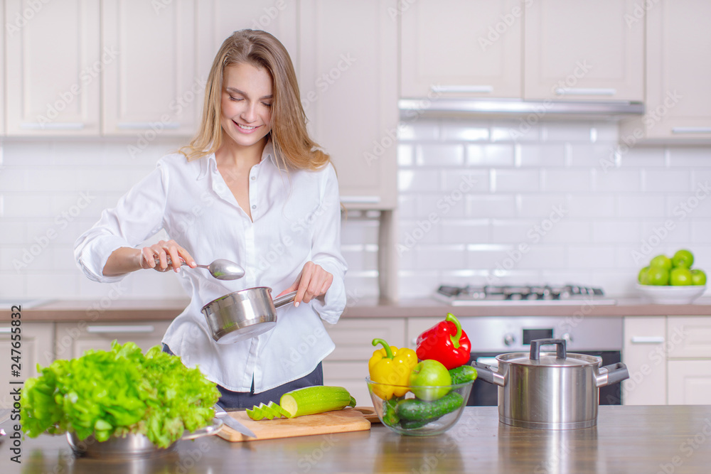 Happy young girl preparing healthy food in the kitchen