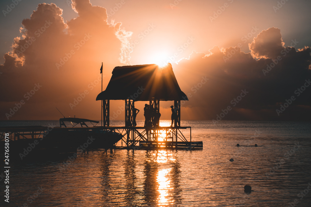 Beautiful sunset in Trou aux Biches, Mauritius. View of the jetty and boats amidst palm trees Beautiful sunset in Trou aux Biches, Mauritius. View of the jetty and boats amidst palm trees