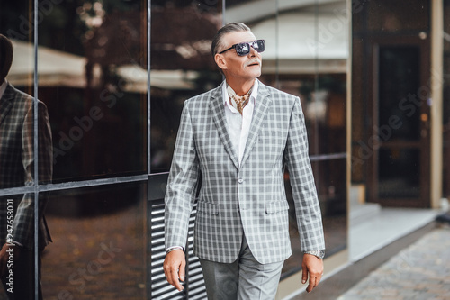 Older gorgeous man walking in the strret and wearing stylish suit photo