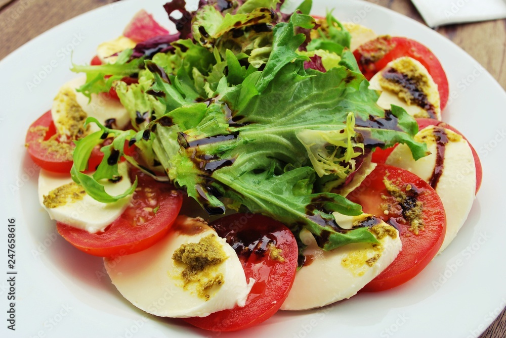 Tomato, Mozzarella Cheese, vinaigrette Salad on a white Plate Tomato, Mozzarella Cheese, vinaigrette Salad on a white Plate