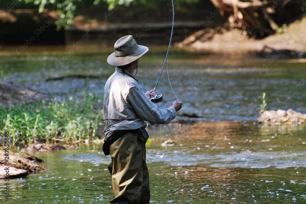 Man Fly Fishing in River, wearing fishing waders, hat, long sleeve shirt.  Stock Photo | Adobe Stock