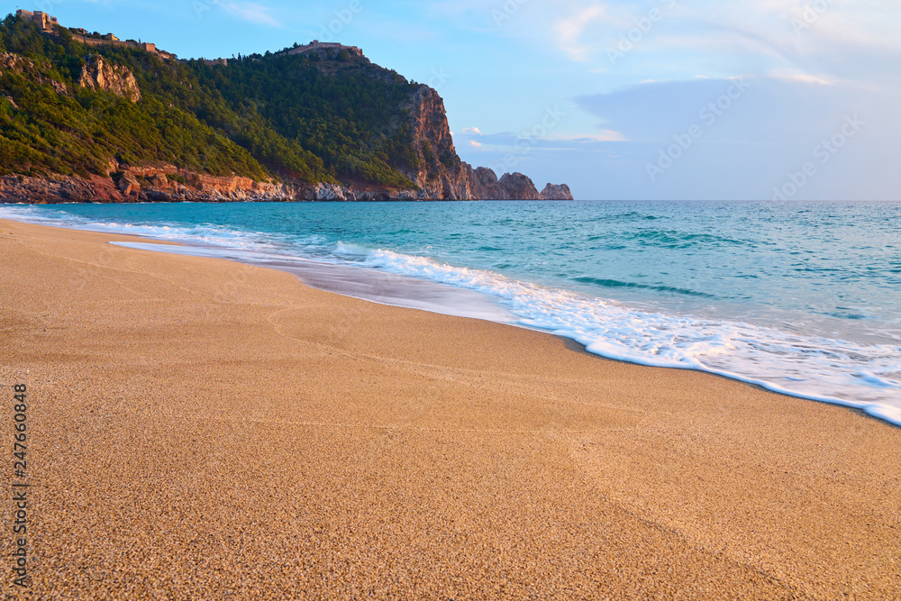 Fototapeta premium Alanya Castle (Alanya Kalesi) on the top of peninsula. View on sea from sandy Cleopatra Beach, Alanya, Turkey in evening.