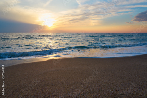  Tropical sandy beach. Sunset seascape. Waves with foam hitting sand.