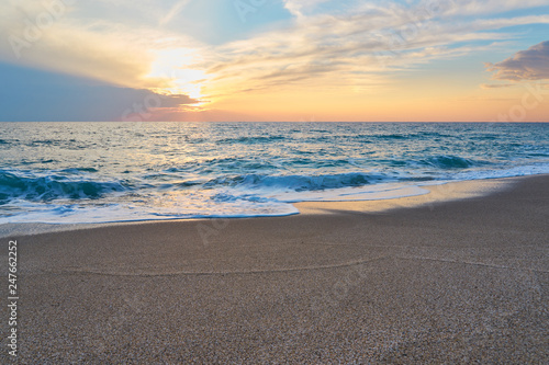  Tropical sandy beach. Sunset seascape. Waves with foam hitting sand.