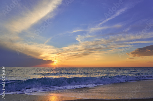  Tropical sandy beach. Sunset seascape. Waves with foam hitting sand.