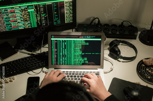Hooded computer hacker using laptop