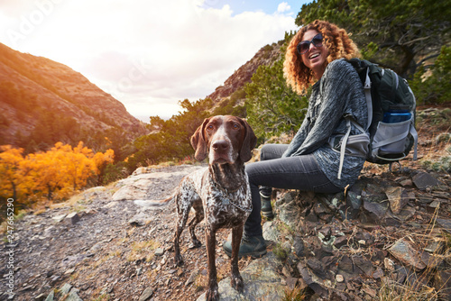 Fotografia a young woman and her dog hiking to the top of a mountain