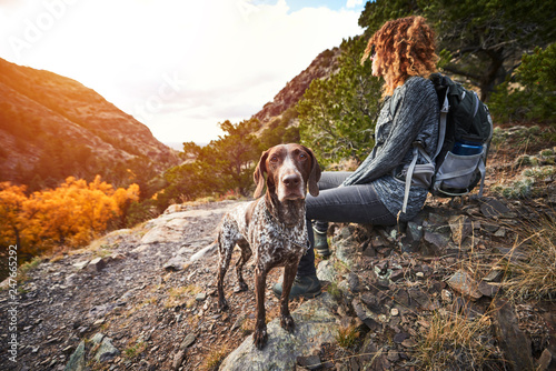 фотография a young woman and her dog at the top of a mountain