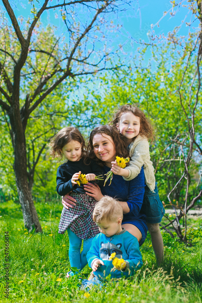 Mom with three children - boy and two girls smiling, and her children are hugging. Happy large family in nature. Mom with three children - boy and two girls smiling, and her children are hugging. Happy large family in nature.