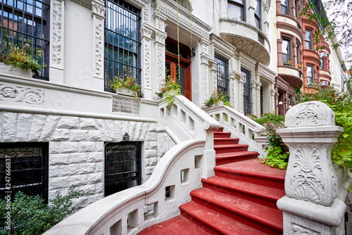 a row of brownstone buildings and stoops in an iconic neighborhood of Manhattan, New York City.