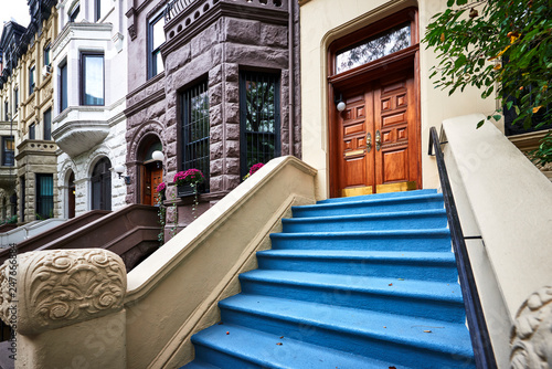 a row of brownstone buildings and stoops in an iconic neighborhood of Manhattan, New York City.