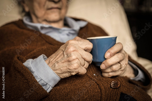 Elderly woman relaxing at home with drink.