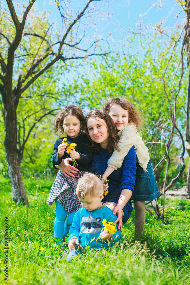 Mom with three children - boy and two girls smiling, and her children are hugging. Happy large family in nature. Mom with three children - boy and two girls smiling, and her children are hugging. Happy large family in nature.