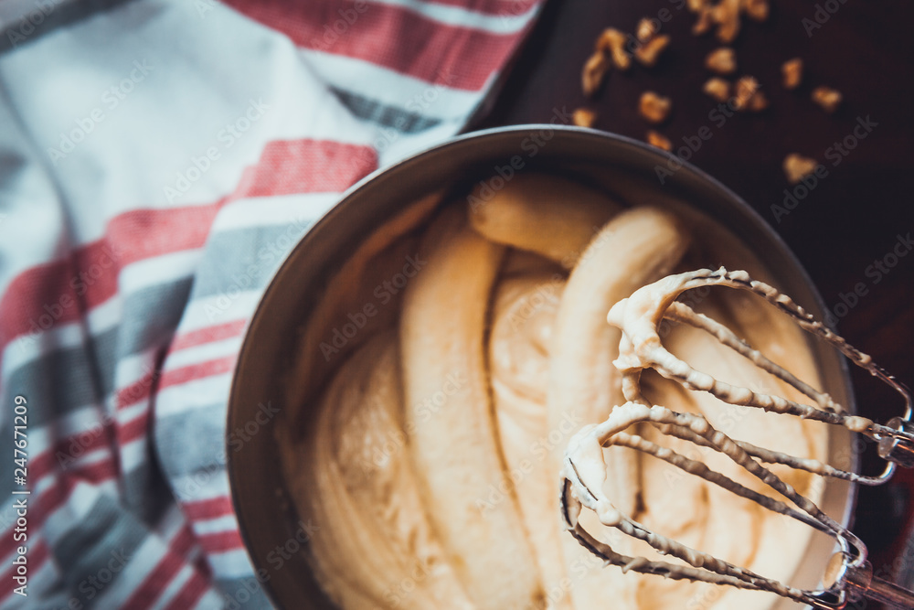 Fototapeta premium Banana Bread Batter Being Mixed In A Stainless Steel Bowl On A Wooden Table
