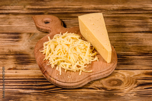 Cutting board with grated cheese on wooden table
