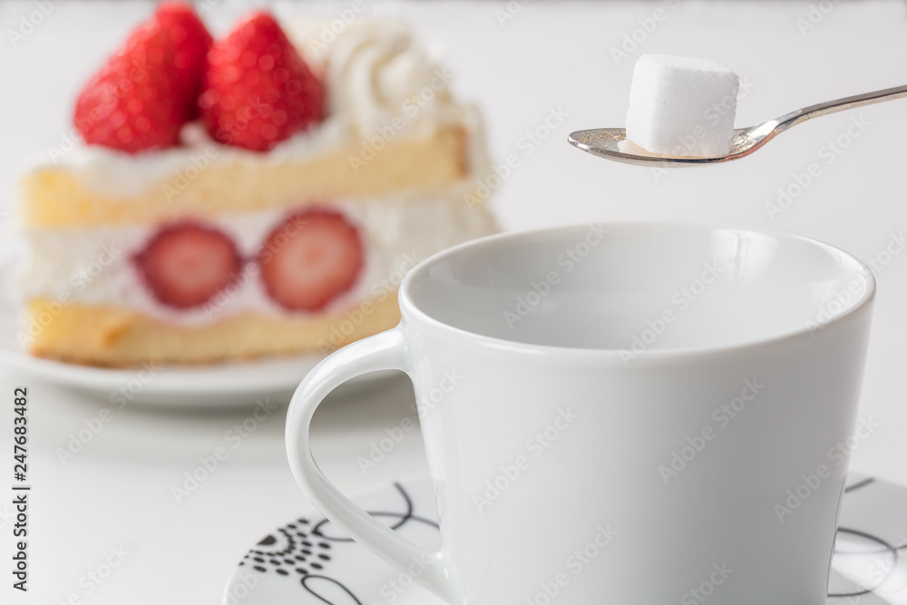 休憩中のショートケーキと紅茶(角砂糖を入れるシーン) 休憩中のショートケーキと紅茶(角砂糖を入れるシーン)