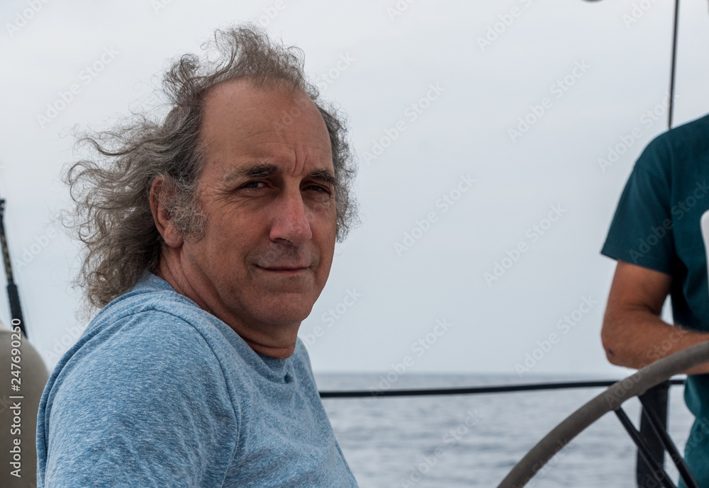 Closeup of an older man sitting on a sailboat smiling