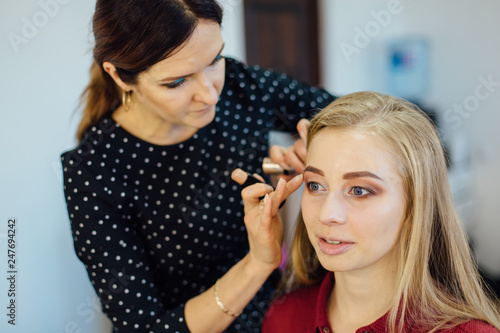 Make-up artist doing make up to the model in studio.