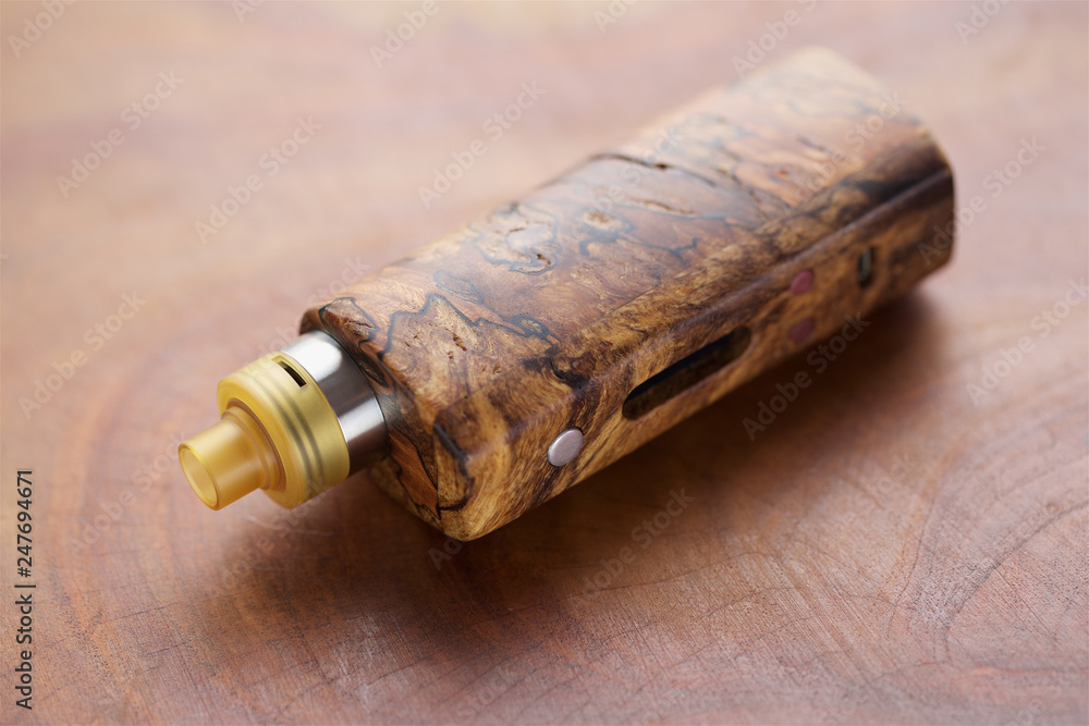high end rebuildable dripping atomizer with stabilized wood regulated box mods on natural wood texture background, vaping device, selective focus