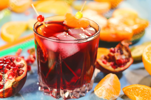 Pomegranate juice in a glass with pieces of ice on the background of cut citrus fruits.