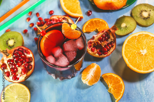 Fototapeta Naklejka Na Ścianę i Meble -  Pomegranate juice in a glass with pieces of ice on the background of cut citrus fruits.