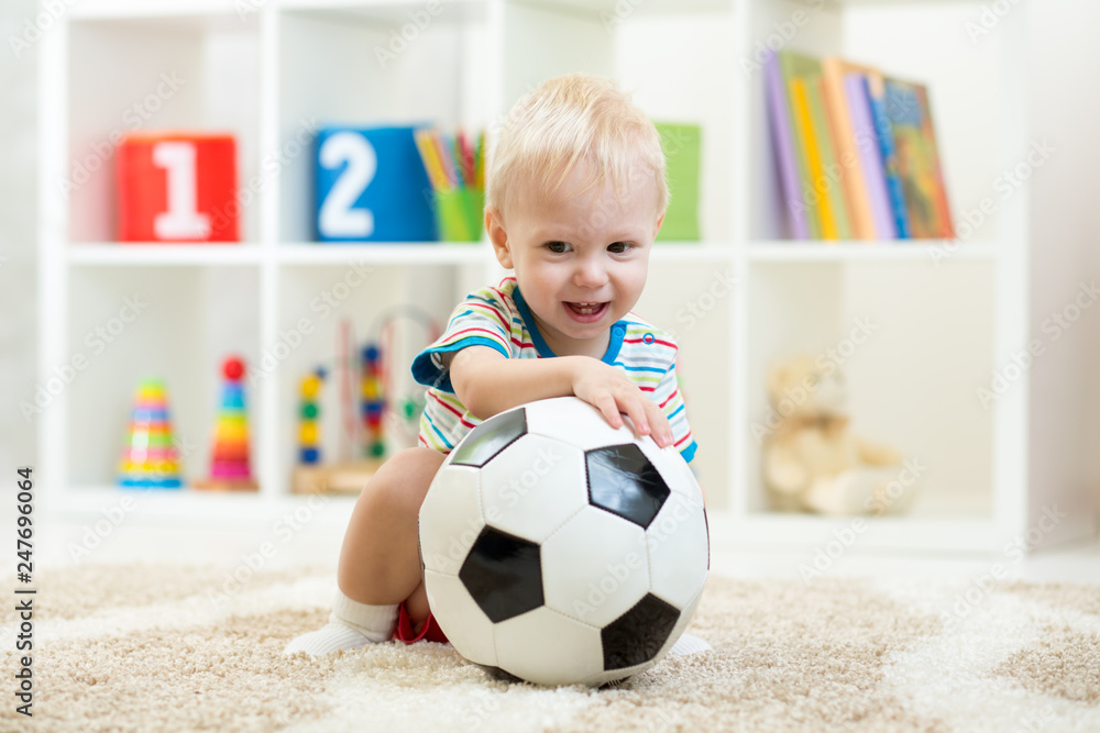 Nursery child boy playing with soccer-ball at home or daycare Nursery child boy playing with soccer-ball at home or daycare