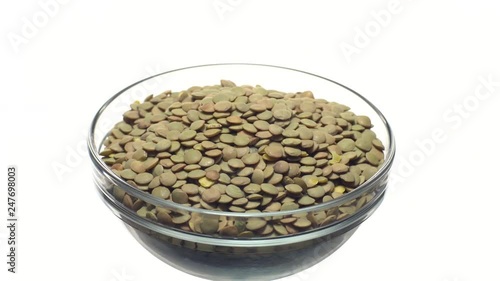 Lentils. Rotation. Close up. Heap of raw uncooked brown lentils in a bowl in rotation.  Food background.  Isolated on white, studio shot. Healthy organic food diet concept photo