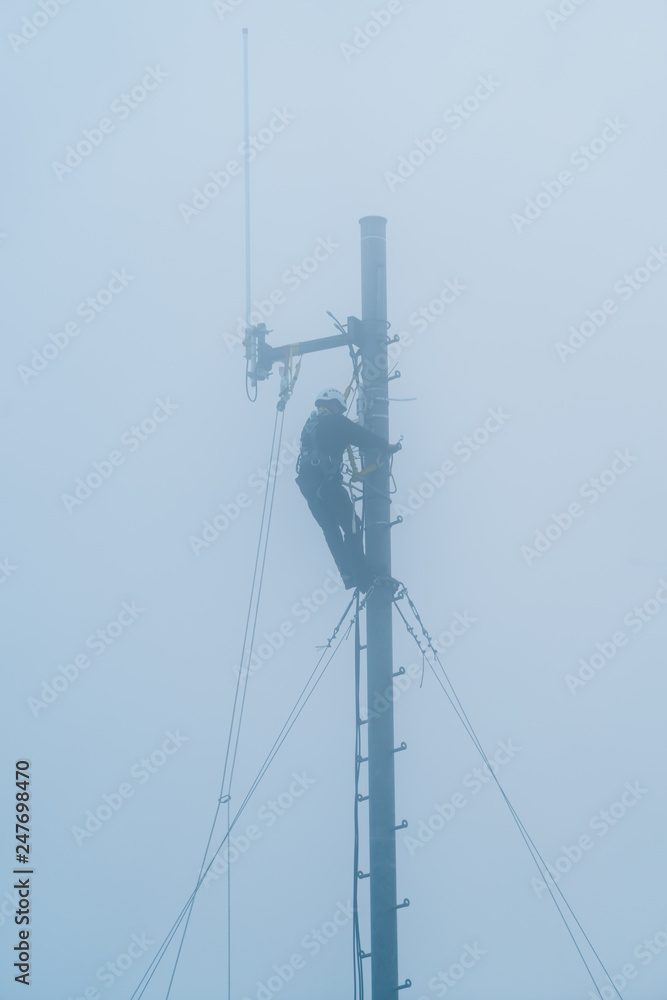 Electrician on power poll in the fog Electrician on power poll in the fog