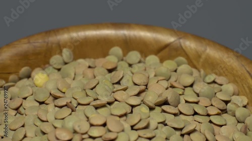 Lentils. Rotation. Close up. Heap of raw uncooked brown lentils in a bowl in rotation.  Food background.  gray background, studio shot. Healthy organic food diet concept