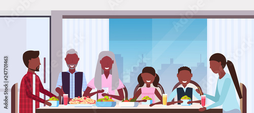 multi generation family sitting around table eating meal together happy african american grandparents parents and children modern kitchen interior closeup portrait flat horizontal