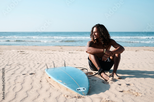 Surfer man with surf board on the beach. Mixed race black skin and beard. Summer sport activity