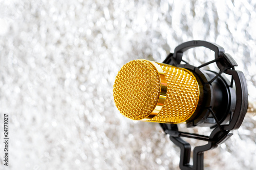 Beautiful golden microphone on a light blurred background, close up, bokeh.