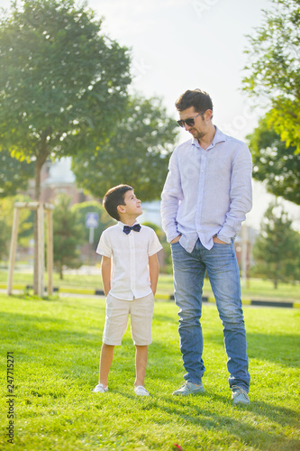 The boy and his father stand in the Park on the green grass and look at each other.