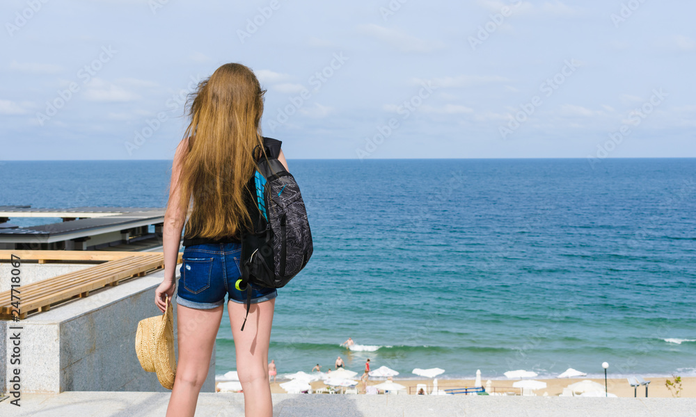 Naklejka premium girl tourist looks over the beach and sea