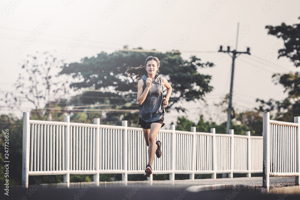 young woman runner running on running road in city park young woman runner running on running road in city park