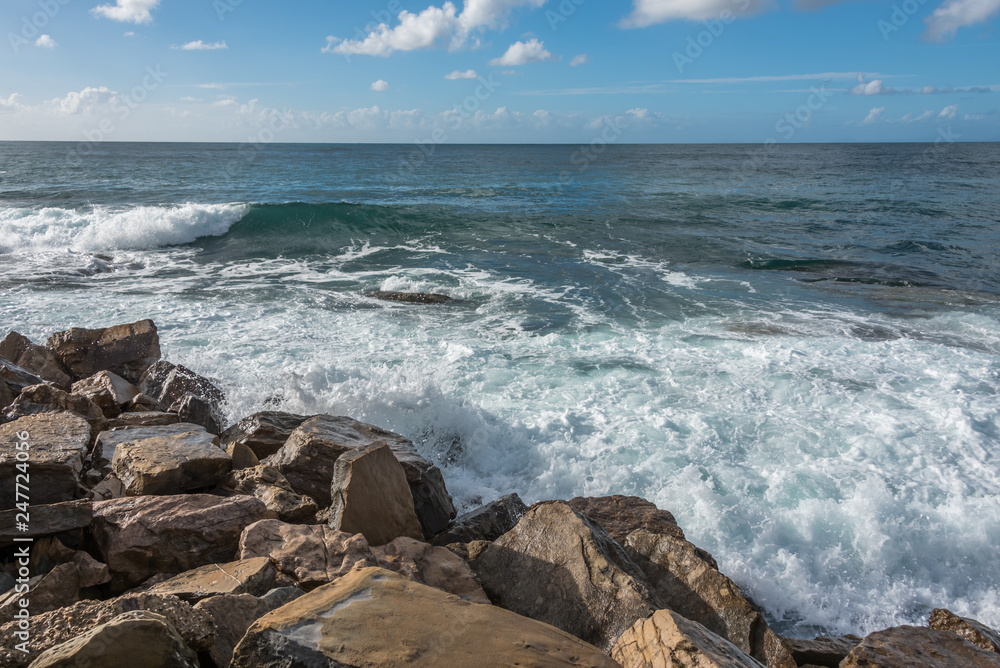 Turquoise Blue Wave Breaking and Washing into a Rocky Shore in Italy Turquoise Blue Wave Breaking and Washing into a Rocky Shore in Italy