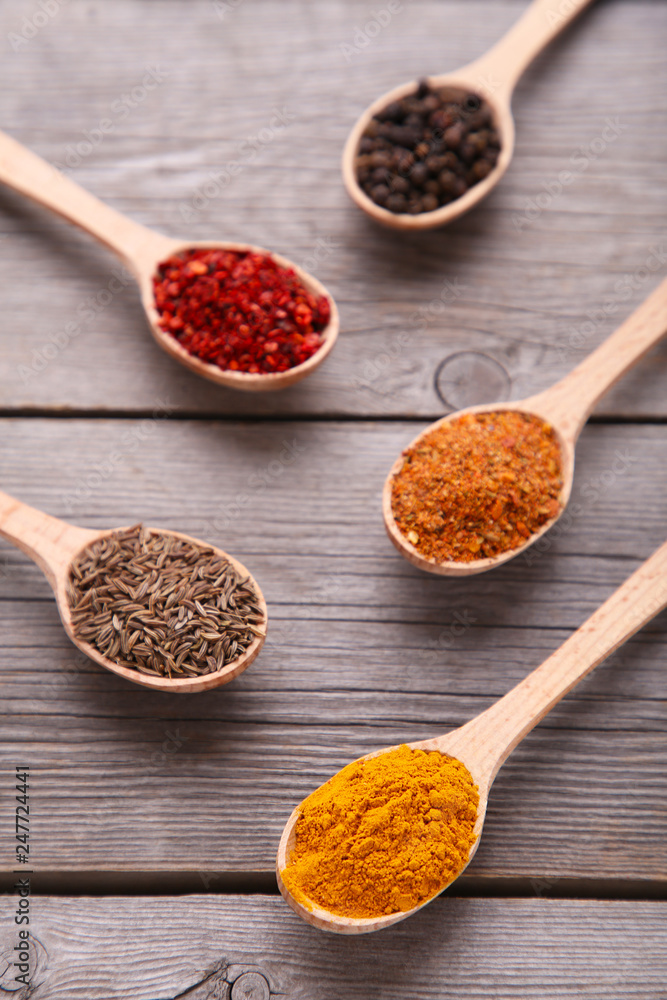 Fototapeta premium Spices mix on wooden spoons on a grey wooden background. Top view