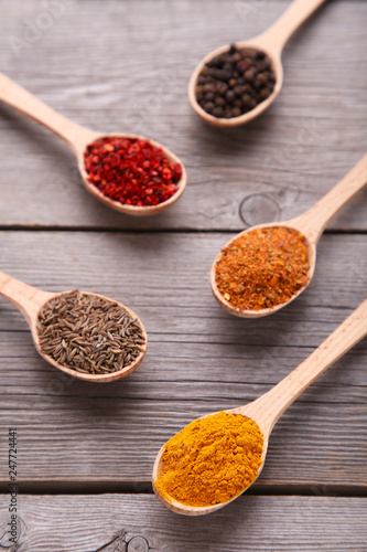 Spices mix on wooden spoons on a grey wooden background. Top view