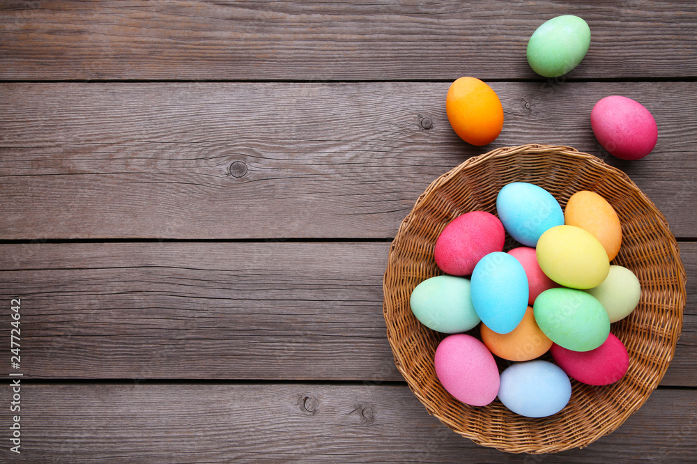 Obraz premium Colorful easter eggs in basket on grey wooden background