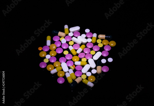 Multicolored pills on black background