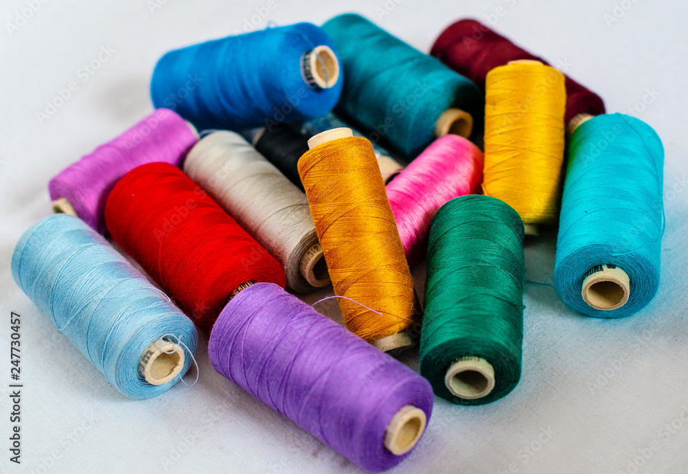 many bright color thread spools on white fabric - image many bright color thread spools on white fabric - image