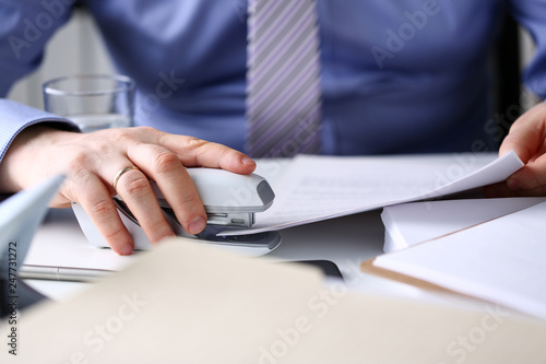 Male clerk arm pin together some papers with stapler photo