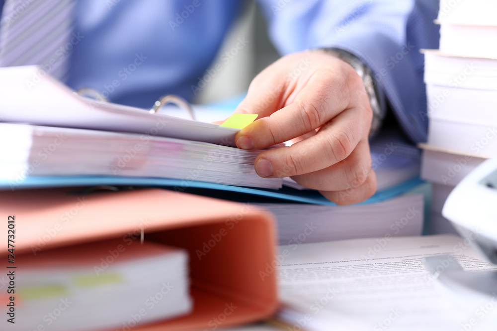 Clerk arm bend over pages in pile of bookmarked documents Clerk arm bend over pages in pile of bookmarked documents