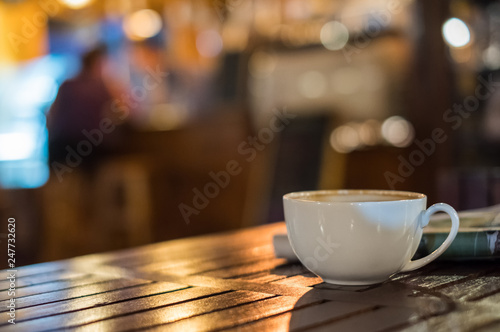 Hot Latte coffee cup on wooden table and glowing bokeh blur background
