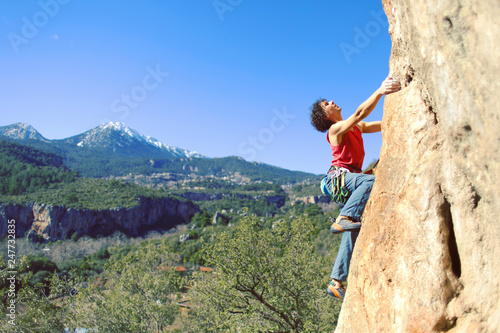 Guy climbing in Greece and beautiful forest and cliff landscape on the background
